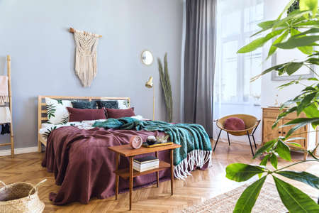 Stylish and luxury interior of bedroom with design furnitures, honey yellow armchair, gray macrame...