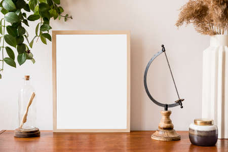 Stylish and retro space of home interior with mock up poster frame, vintage cupboard with retro accessories, flowers in vase, plants and letter in bottle . Nice home decor. Minimalistic concept.の写真素材