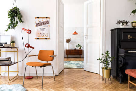 Stylish compositon of retro home interior with mock up poster frame, vintage orange chair,...