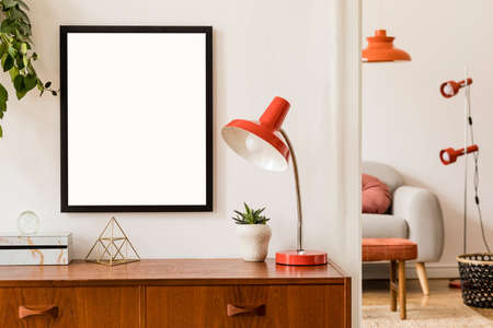 Stylish room of home interior with black mock up frame, design sofa, furnitures, vintage cupboard with elegant accessories, plants and red retro table lamp. Cozy home decor. Minimalistic concept.の写真素材