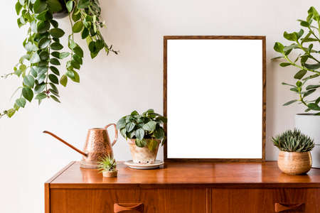 Nice and retro space of home interior with mock up poster frame, vintage cupboard with elegant floral accessories, a lot of plants in stylish pots. Cozy home decor. Minimalistic concept. Home gardenの写真素材