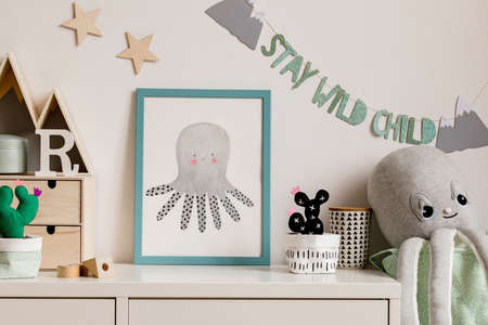 Cozy scandinavian nursery interior with mock up photo frame, plush octopus, cacti and wooden accessories. Hanging stylish inscription and stars on the white background wall. Template. Real photo.の写真素材
