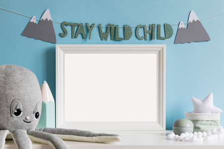 Cozy scandinavian newborn baby room with mock up poster frame, plush octopus ,mint crayon, boxes,...