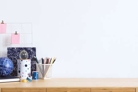 Cosmic and stylish home office interior with wooden desk, cool office accessories, tapes, supplies, notebooks, memo sticks, pencils. Modern home decor. Minimalistic concept. Template. Copy spce.の写真素材