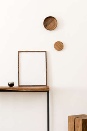 Design scandinavian interior of living room with wooden console, rings on the wall, mock up poster frame, wooden cube and elegant personal accessories. Modern home decor. Template. White walls.の写真素材