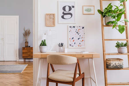 Design scandinavian interior of home office space with stylish chair, wooden desk, ladder, cube,...
