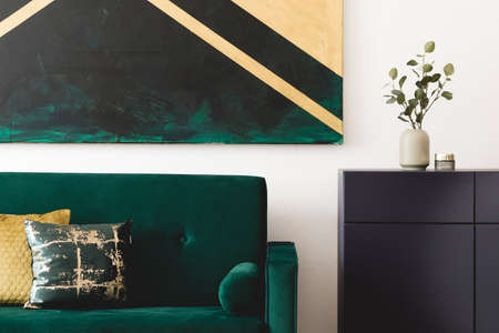 Stylish composition of home interior design with modern velvet sofa, navy blue shelf, pillows,...