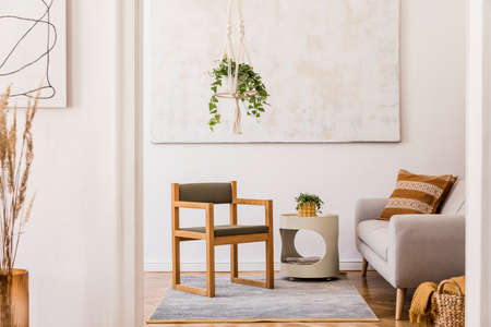 The design boho interior of living room in cozy apartment with design coffee table, gray sofa, honey...