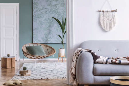 Modern and bohemian composition of interior design at apartment with gray sofa, rattan armchair,...