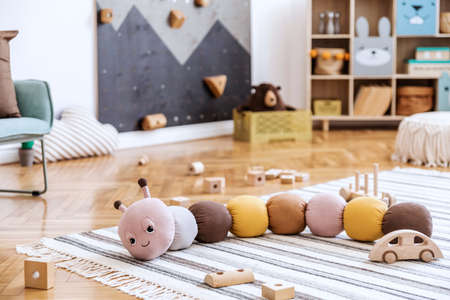 Stylish scandinavian newborn baby room with toys, children's armchair, teddy bear, soft toys and...