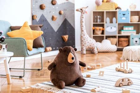 Modern scandinavian interior design of childroom with mint armchair, climbing wall for kids, design furnitures, soft toys, teddy bear and cute children's accessories. Stylish kidroom decor. Template.の写真素材