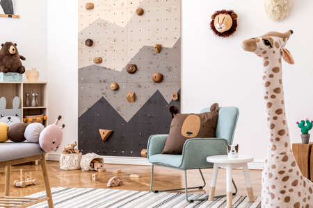 Modern scandinavian interior design of childroom with mint armchair, climbing wall for kids, design furnitures, soft toys, teddy bear and cute children's accessories. Stylish kidroom decor. Template.の写真素材
