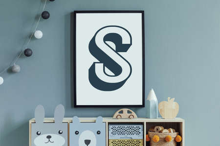 Stylish scandinavian newborn baby room with wooden cabinet, toys, mock up poster frame and children's accessories. Modern interior with eucalyptus background wall and cottona balls. Modern home decor.の写真素材