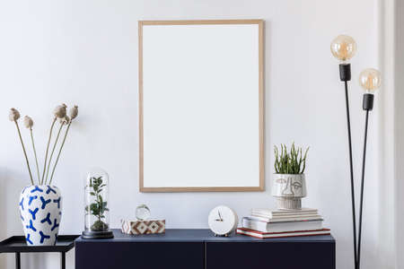 Stylish scandinavian interior design with mock up picture frames, navy blue commode, flowers in...