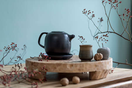 Stylish autumn composition of home decor on living room with wooden fruit tray, cement fruits, tea jug and autumn flowers. Eucalyptus color concpet. Template. Modern decoration. Close up.の写真素材