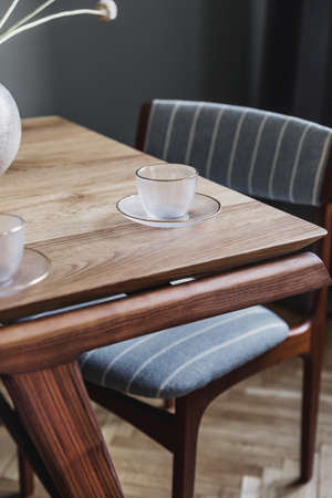 Stylish and modern dining room interior with design sharing table, chairs, glamor decoration and elegant accessories. Flowers in vase. Template. Interior design. Home decor.の写真素材