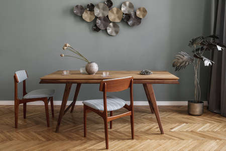 Modern and stylish dining room interior with glamor wooden table, elegant chairs and design decoration. Template. Home decor. Gray background wall. Minimalistic concept of interior design.の写真素材