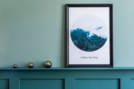 Stylish living room interior at elegant apartment with mock up poster frame, and elegant glassy accessories on the shelf. Green wood paneling. Modern home staging. Template. Home decor.の写真素材