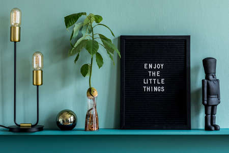 Stylish living room interior at apartment with mock up poster frame, plant, dried flowers, decoration and elegant personal accessories on the shelf. Green wood paneling. Modern home staging. Template.の写真素材