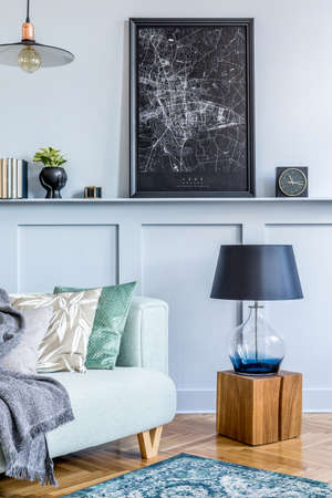 Stylish interior of living room with mock up poster frame, design sofa, wooden cube, pendant lamp,...