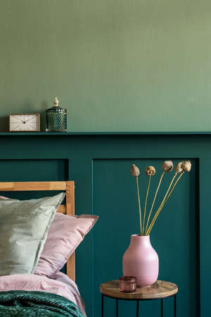 Modern bedroom interior with design coffee table, flowers in vase and elegant personal accessories. Beautiful bed sheets, blanket and pillows. Template. Stylish home staging. Wall panelling. Detailsの写真素材