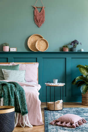 Stylish composition of bedroom interior with wooden bed, design furnitures, shelf, plants, decor and elegant personal accessories. Beautiful bed sheets, blanket and pillow. Template. Home staging.の写真素材