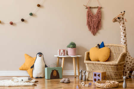 Stylish scandinavian interior of child room with natural toys, hanging decoration, design furniture, plush animals, teddy bears and accessories. Beige walls. Interior design of kid room. Template.の写真素材