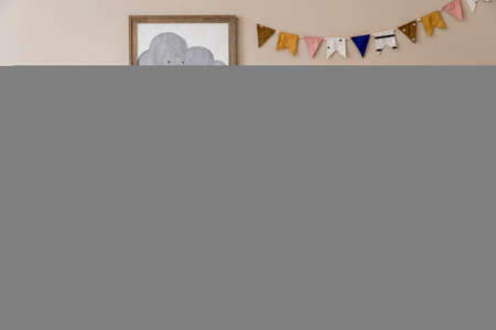 Stylish scandinavian kid room with mock up poster, toys, teddy bear, plush animal, natural pouf and children accessories. Modern interior with beige background walls. Template. Design home staging.の写真素材