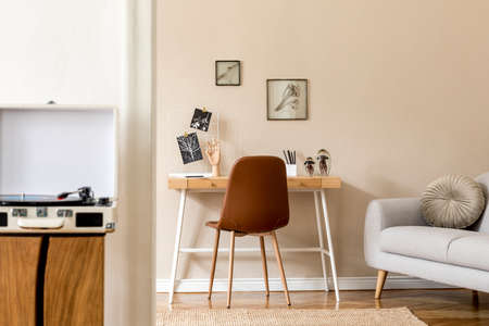 Interior design of scandinavian open space with mock up photo frames, wooden desk, gray sofa, cacti,...