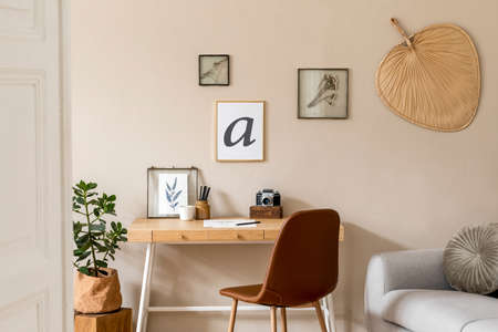 Interior design of scandinavian open space with mock up photo frames, wooden desk, gray sofa, plant, books office and personal accessories. Stylish neutral home decor. Beige walls. Template.の写真素材