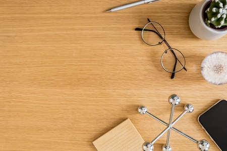Stylish flat lay business composition on the wooden desk with glasses, notes, pen, copy space and office supplies in modern concept.の写真素材