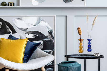 Stylish interior of living room with design gray armchair, pillows, coffee table, paintings, dried flower in vase, decoration and elegant personal accessories in modern home decor.の写真素材