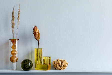 Minimalistic composition on the wooden shelf with dried flowers in vase and elegant personal accessories in stylish living room interior. Copy space.の写真素材