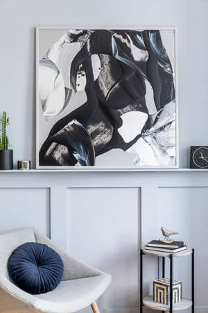 Stylish interior of living room with design gray armchair, pillows, marble stool, paintings, cacti,...
