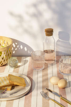 Stylish composition of outdoor kitchen space with wooden table, food, drinks, kitchen accessories,...