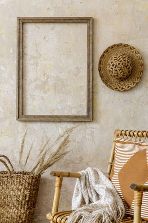 Stylish and beige composition of home interior with rattan armchair, mock up poster frame, coffee...