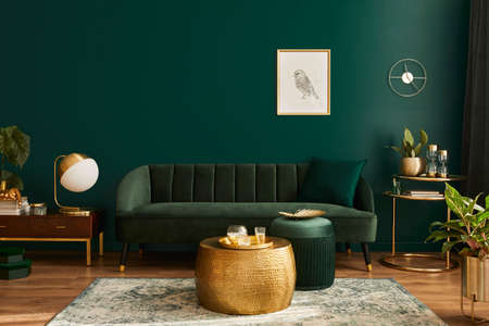 Luxury living room in house with modern interior design, green velvet sofa, coffee table, pouf, gold...
