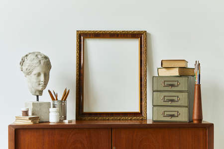 Stylish composition of artist workspace room with design retro teak commode, mock up poster frame, book, decoration and painting accessories. Template.の写真素材