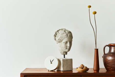 Scandinavian interior with stylish teak commode, design decoration, dried flowers in vase, clock, copy space and elegant personal accessories. Neutral living room in classic house. Template.の写真素材