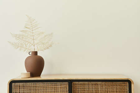 Modern scandinavian home interior with design wooden commode, dried leafs in ceramic vases and...