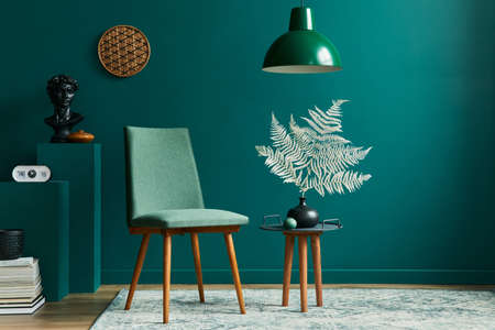 Stylish concept of living room interior with small table, design chairs, dried leaf in beige vase, clock, retro carpet, decoration and accessories in modern vintage home decor.の写真素材