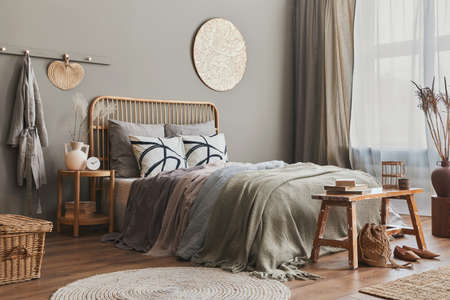 Wooden bed in stylish neutral bedroom interior with design furniture, decoration, carpet, bench,...