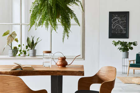 Stylish and cozy interior of dining room with design craft wooden table, chairs, plants, velvet...