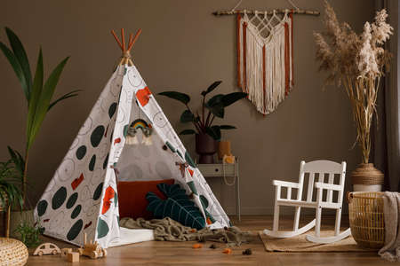 Creative composition of stylish child room inerior design with hat, plants, toys, hanging decoration...