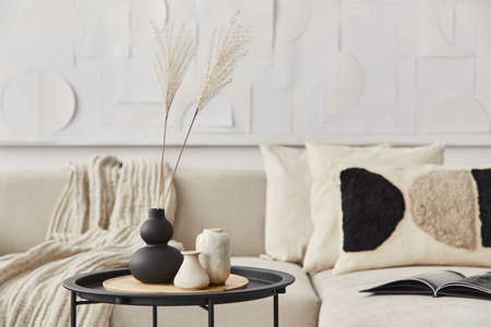 Stylish composition at fancy interior with wooden coffee table, dried flowers in vase, pillow,...