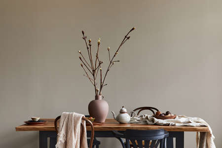 Stylish rustic interior of dining room with walnut wooden table, retro chairs, decoration, dried...