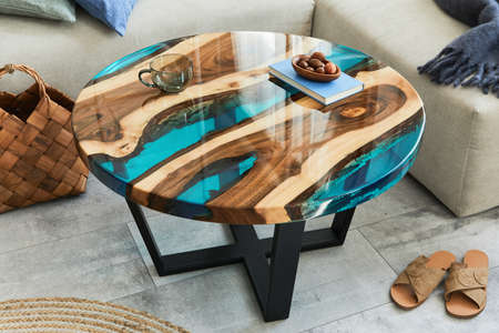 Stylish composition with design epoxy coffee table, sofa, blanket, pillows, book, decoration and personal accessories in modern home decor. Template. Details.の写真素材