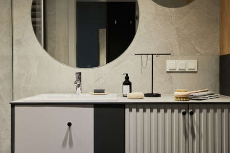 Stylish composition of modern bathroom interior. Modern mixed wooden commode, mirror and personal...