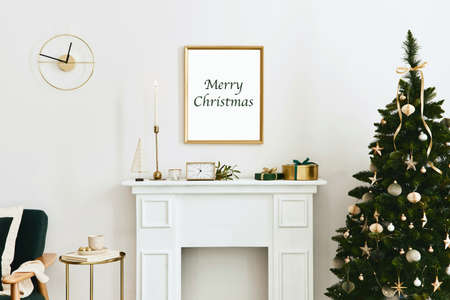 Christmas composition with gold mock up poster frame, white chimney and decoration. Christmas trees and wreath, candles, stars, light and elegant accessories. Template.の写真素材