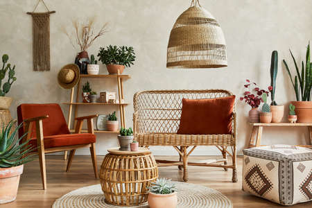 Stylish composition of cozy living room interior with copy space, lot of plants, wooden shelves, rattan sofa and accessories. Beige wall, carpet on the floor. Plants love concept. Template.の写真素材